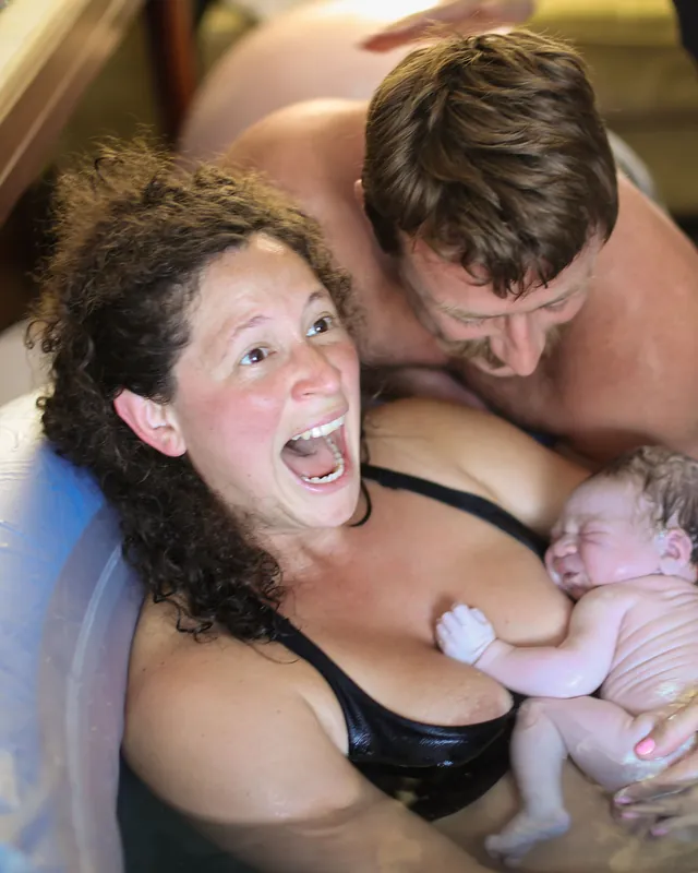 A mother's joy the moment her baby arrives in the birth pool, Orange County birth photography by Jenn Miller