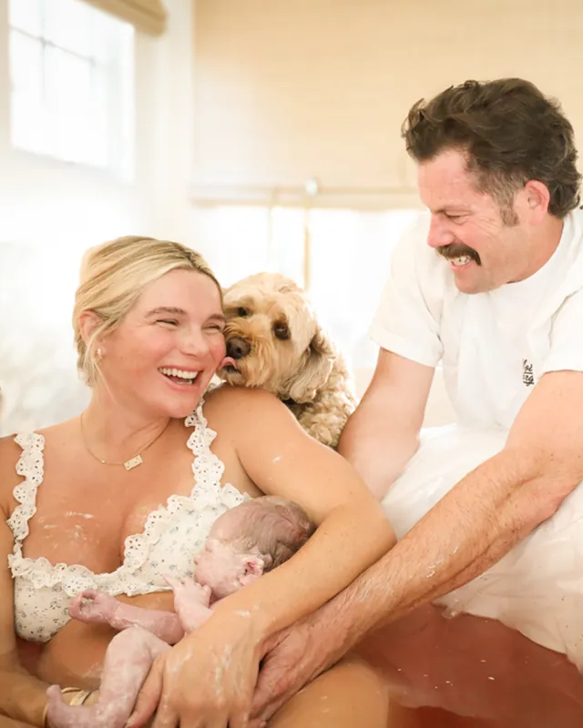 A family laughing together with their newborn moments after a home water birth, Orange County birth photography by Jenn Miller