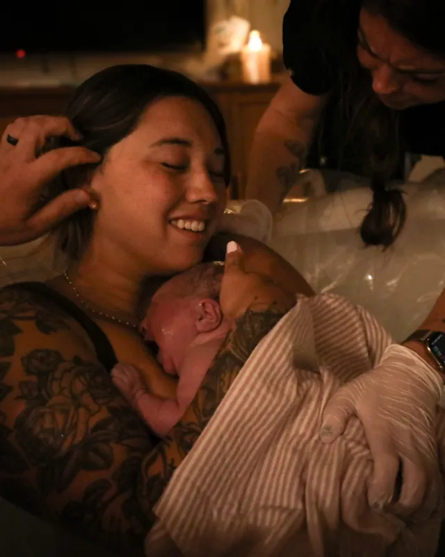 A mother cheek to cheek with her newborn by candlelight, Orange County birth photography by Jenn Miller