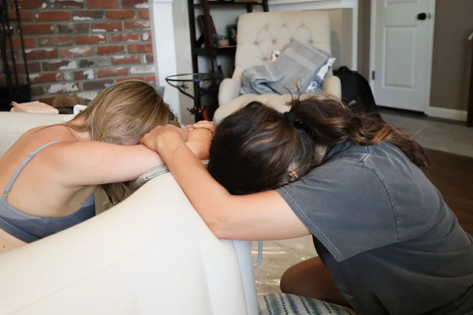 Jenn Miller resting her head beside a laboring mother at the birth pool