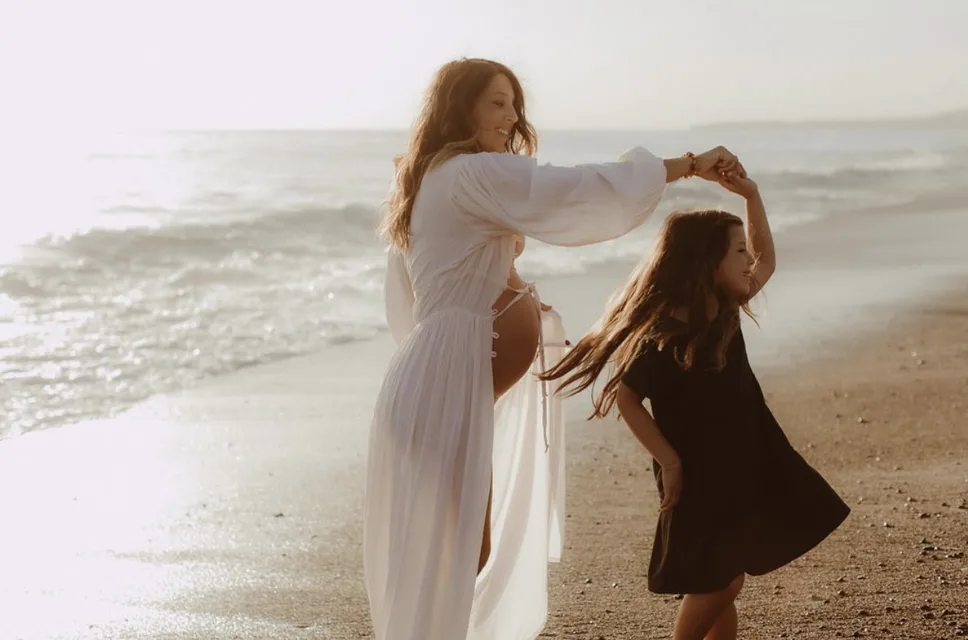 Jenn Miller, pregnant, dancing on the beach with one of her children